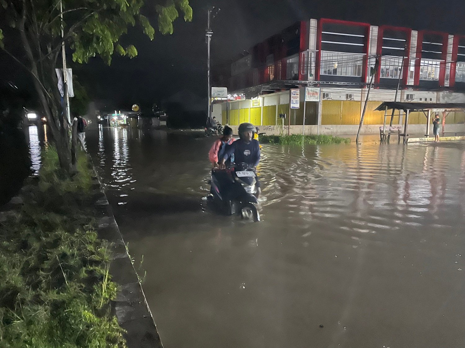 Ket: Seorang warga Kota Sorong mendorong kendaraan yang terjebak di tengah genangan banjir di depan Jupiter-Kilo 10 masuk Kota Sorong, Minggu (22/6/2025). Genanan air akibat banjir tersebut hampir meluas di sejumlah titik di Kota Sorong, Papua Barat Daya/Foto: Petrus Rabu