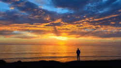 Ilustrasi: Pria menikmati senja sendirian di tepi pantai. (Image by wirestock on Freepik)