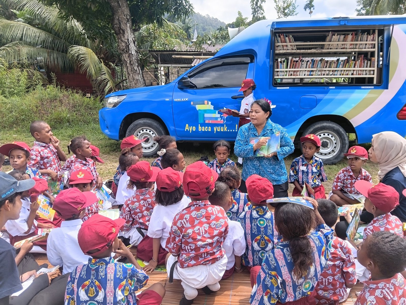 Ket: Ketua Tim Penggerak PKK Raja Ampat, Ny. Rusmiati Burdam (berlutut) mengajar dan memberikan penjelasannya tentang penting membaca bagi anak-anak SD YPK Sion Warsambin, Kampung Warsambin, Distrik Teluk Mayalibit, Kamis (23/7/2026)/Sumber Foto: Prokopim Setda Raja Ampat,